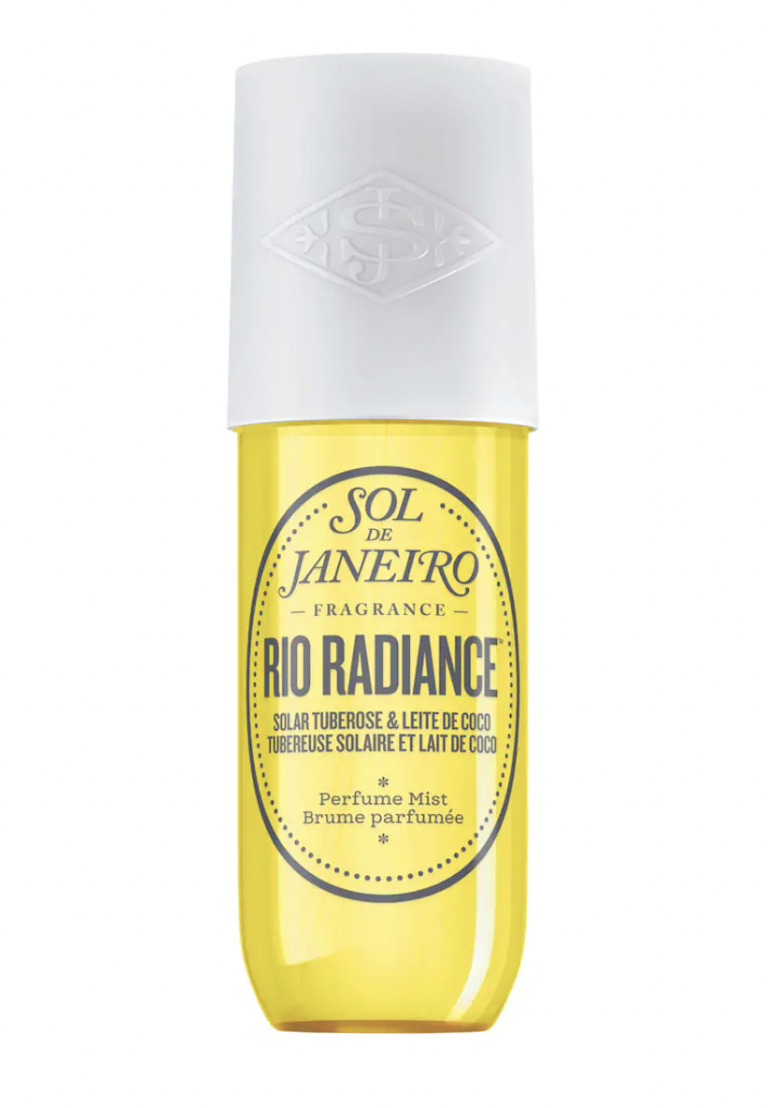 A bottle of Sol de Janeiro's Brazilian Crush Cheirosa '87 fragrance mist, featuring a bright yellow liquid in a clear bottle with a white cap. The label describes the scent as containing notes of solar tuberose and leite de coco.